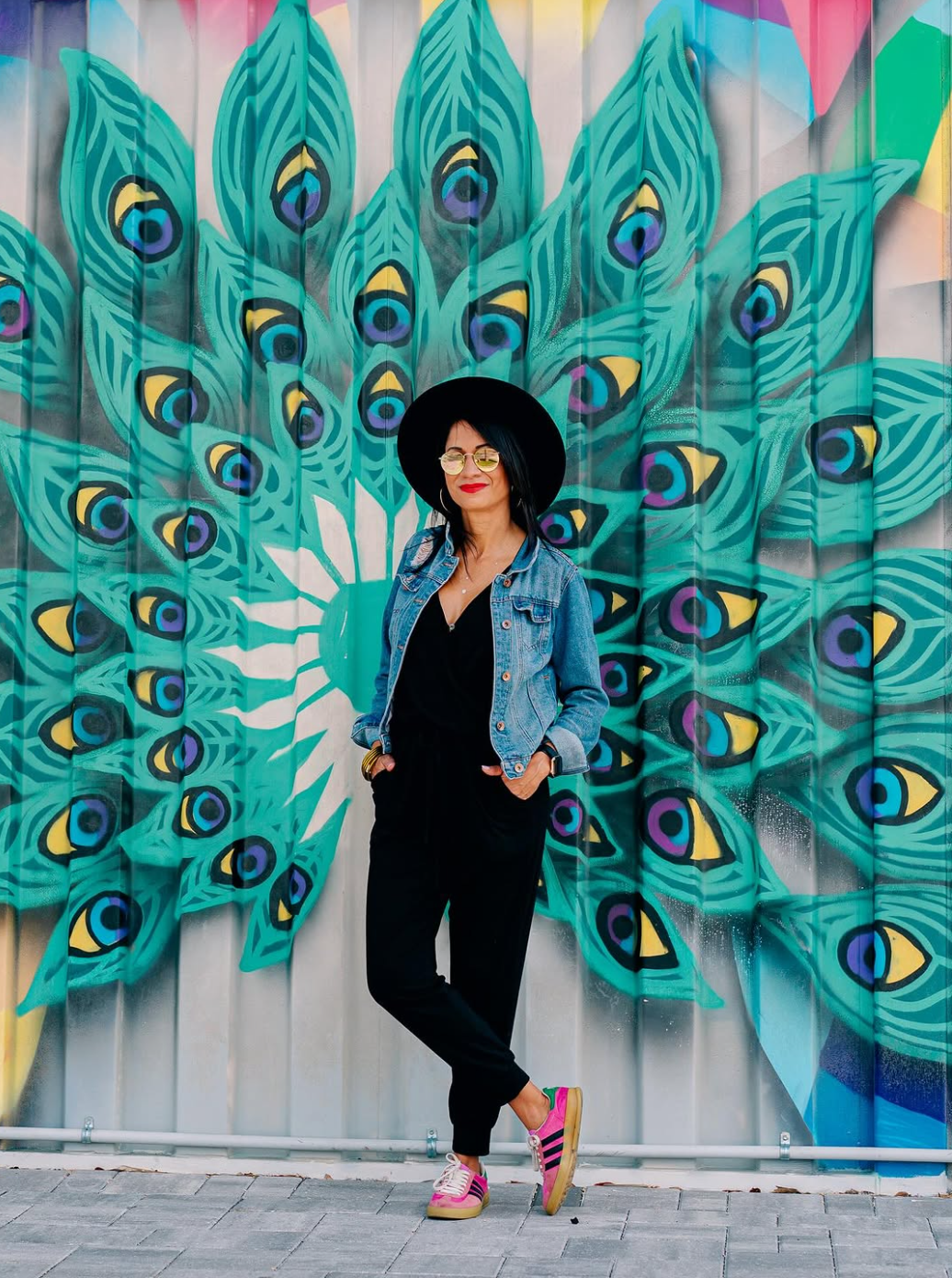 Bridgette, founder of Babe Coffee Lounge, standing in front of a colorful peacock mural
